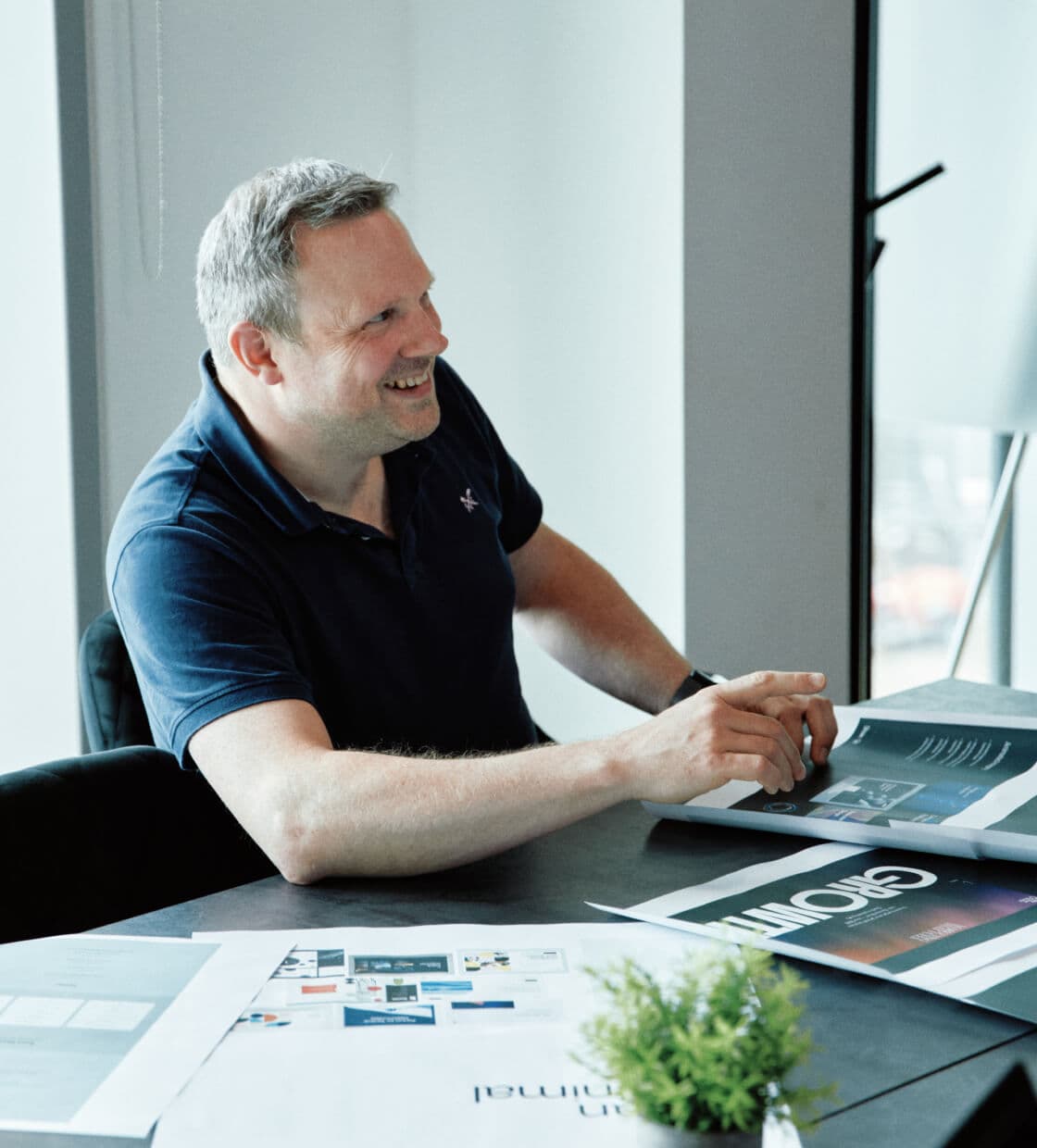 Team member actively participating in a feedback session, speaking with energy and gesturing toward a presentation board.