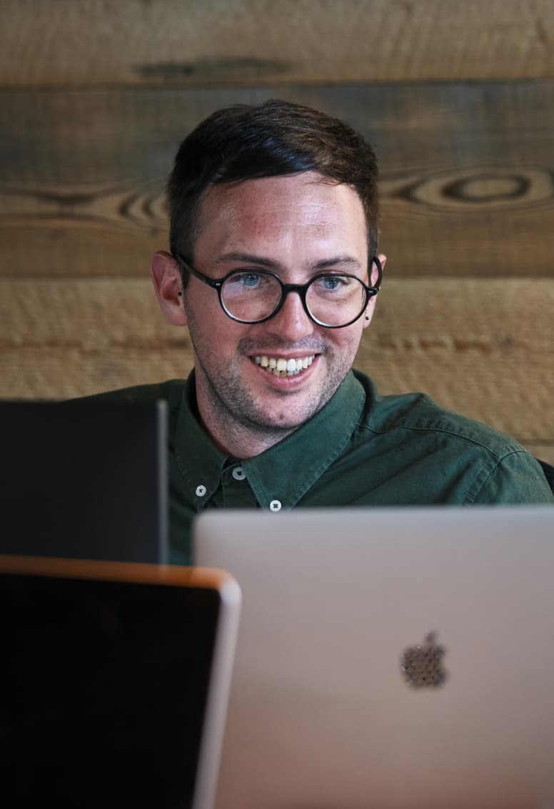 Team member focused on work, typing on a laptop at a desk in a modern office setting.